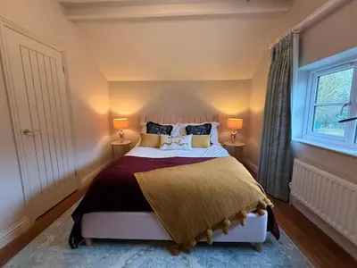 a bedroom with a large bed with two lamps at The Old Coach House in Hockwold cum Wilton