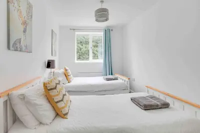 two beds in a white room with a window at Blackwater Villa Witham in Witham