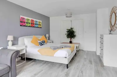 a white bedroom with a bed and a chair at Blackwater Villa Witham in Witham