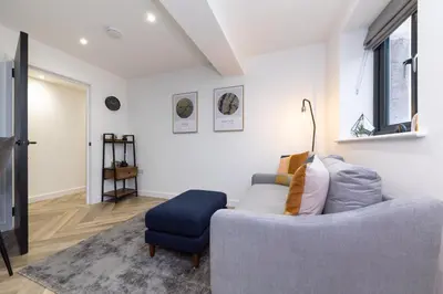 a living room with a blue chair and a couch at Flat in Royston Town Centre in Royston