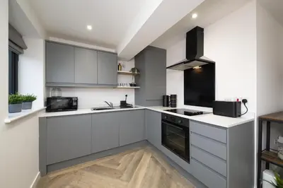 a kitchen with white cabinets and a black appliance at Flat in Royston Town Centre in Royston