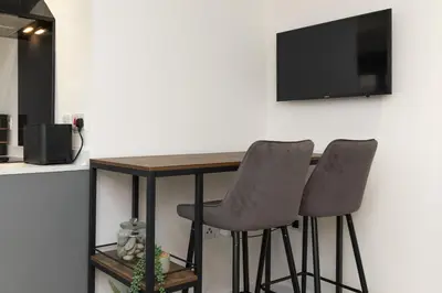 a kitchen table with two chairs and a television on a wall at Flat in Royston Town Centre in Royston