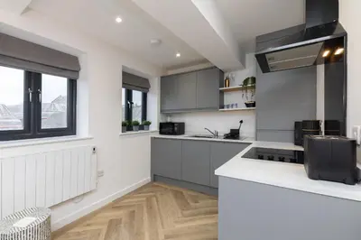 a kitchen with white and gray cabinets and a window at Flat in Royston Town Centre in Royston