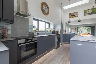 a kitchen with blue cabinets and a clock on the wall at 4 Bed in Saham Toney oc-o30348 in Saham Toney