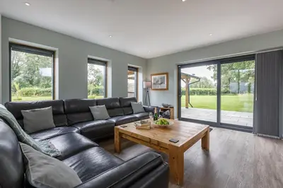 a living room with a black leather couch and a table at 4 Bed in Saham Toney oc-o30348 in Saham Toney