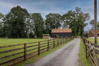 a dirt road next to a fence with a barn at 4 Bed in Saham Toney oc-o30348 in Saham Toney
