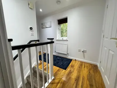 a hallway with white walls and a staircase with a window at A luxurious coach house in Colchester