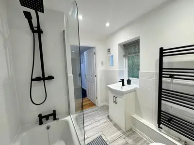 a bathroom with a shower and a tub and a sink at A luxurious coach house in Colchester