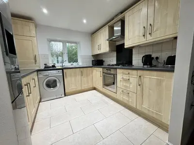 a kitchen with wooden cabinets and a washer and dryer at A luxurious coach house in Colchester