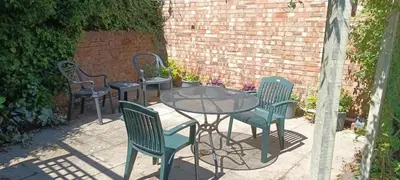 a patio with three chairs and a glass table and chairs at Compass Barn, Wenhaston in Wenhaston