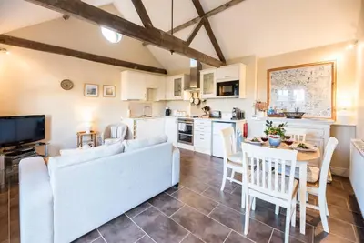 a kitchen and living room with a couch and a table at Compass Barn, Wenhaston in Wenhaston