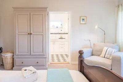 a bedroom with a bed and a chair and a closet at Compass Barn, Wenhaston in Wenhaston