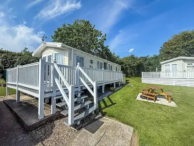 a white house with a porch and a picnic table at Beautiful Caravan With Decking & Wifi At Carlton Meres Park Ref 60002R in Saxmundham