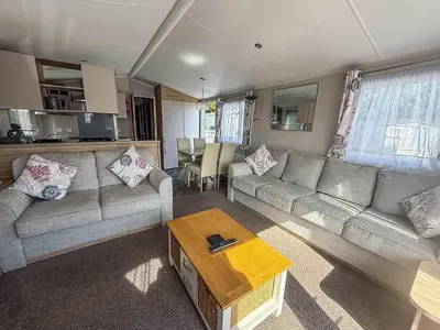 a living room with a couch and a table at Beautiful Caravan With Decking & Wifi At Carlton Meres Park Ref 60002R in Saxmundham