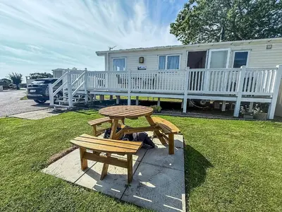 a picnic table and bench in front of a house at Beautiful Caravan With Decking & Wifi At Carlton Meres Park Ref 60002R in Saxmundham