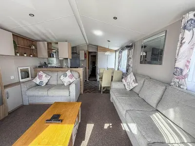 a living room with a couch and a table at Beautiful Caravan With Decking & Wifi At Carlton Meres Park Ref 60002R in Saxmundham