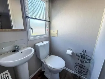 a bathroom with a white toilet and a sink at Beautiful Caravan With Decking & Wifi At Carlton Meres Park Ref 60002R in Saxmundham