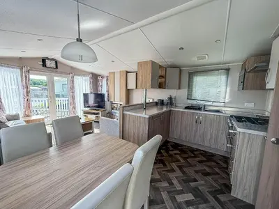 a kitchen and dining room with a table and chairs at Beautiful Caravan With Decking & Wifi At Carlton Meres Park Ref 60002R in Saxmundham