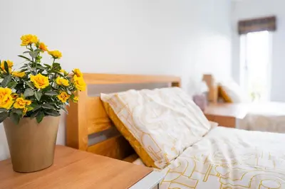 a bedroom with a bed and a vase of flowers on a table at East Wing at Champaignes Toft, Mendlesham in Stowmarket