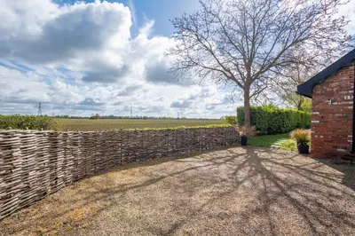 a brick fence and a tree in a field at East Wing at Champaignes Toft, Mendlesham in Stowmarket