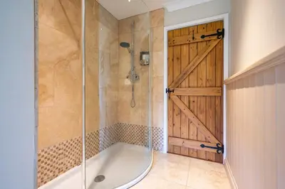 a bathroom with a tub and a shower with a door at East Wing at Champaignes Toft, Mendlesham in Stowmarket