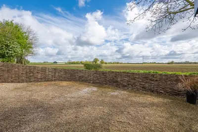 a brick wall with a field in the background at East Wing at Champaignes Toft, Mendlesham in Stowmarket
