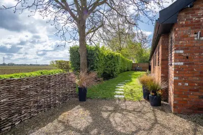 a brick building with potted plants next to a wall at East Wing at Champaignes Toft, Mendlesham in Stowmarket