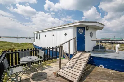 a deck with a small building and a table at Lorna, Houseboat , West Mersea in West Mersea