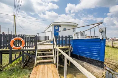 a blue boat with a life preserver on a dock at Lorna, Houseboat , West Mersea in West Mersea