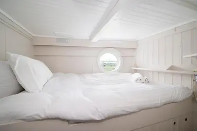 a white bed in a room with a window at Lorna, Houseboat , West Mersea in West Mersea