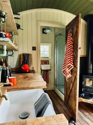 a kitchen with a bed and a sink in a room at Secret Paddock Shepherds Hut in Hollesley