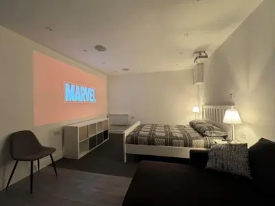 a bedroom with a king sized bed and a chair at Private cinema studio guest house with garden in Brentwood
