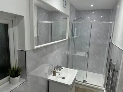 a white bathroom with a shower and a sink at Private cinema studio guest house with garden in Brentwood