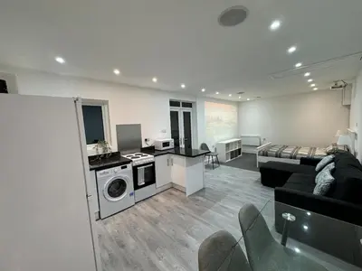 a living room with a kitchen and a living room with a couch at Private cinema studio guest house with garden in Brentwood