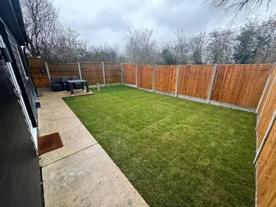 a backyard with a fence and a table and grass at Private cinema studio guest house with garden in Brentwood