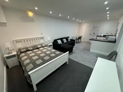 a bedroom with a bed and a living room at Private cinema studio guest house with garden in Brentwood