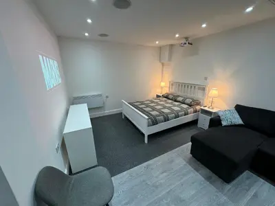 a bedroom with a bed and a couch and a chair at Private cinema studio guest house with garden in Brentwood