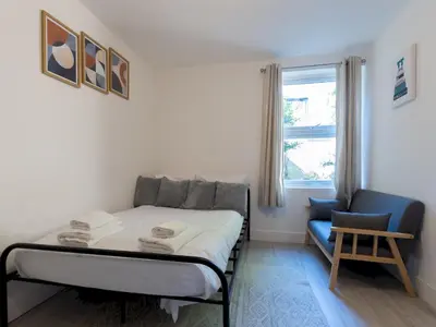 a bedroom with a bed and a chair and a window at Studio flat in Heart of Southend - Pass the Keys in Southend-on-Sea