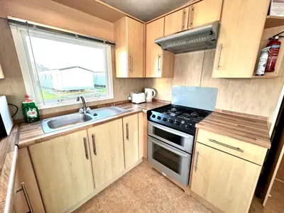a small kitchen with a stove and a sink at Seashell Hideaway Caravan at Seawick Holiday Park in Clacton-on-Sea