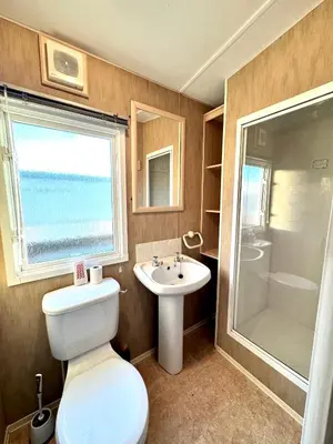 a bathroom with a toilet and a sink and a shower at Seashell Hideaway Caravan at Seawick Holiday Park in Clacton-on-Sea