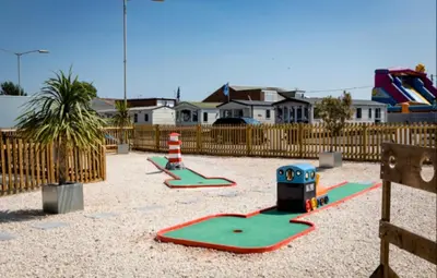 a playground with two play equipment in a yard at Seashell Hideaway Caravan at Seawick Holiday Park in Clacton-on-Sea