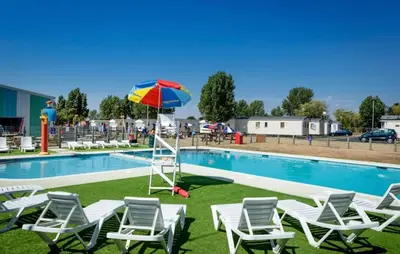 a group of chairs and an umbrella next to a pool at Seashell Hideaway Caravan at Seawick Holiday Park in Clacton-on-Sea