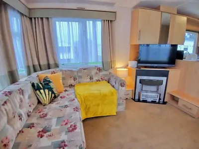 a living room with a couch and a television at Seashell Hideaway Caravan at Seawick Holiday Park in Clacton-on-Sea