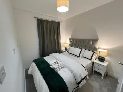 a bedroom with a large bed and two lamps at The Belles' Place near Colchester in Earls Colne