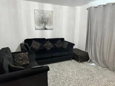 a living room with a black couch and a painting at The Belles' Place near Colchester in Earls Colne
