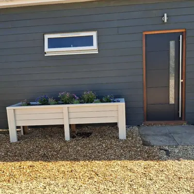 a bench with flowers in it in front of a house at Hazel Cottage in Mildenhall