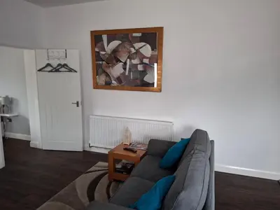 a living room with a couch and a painting on the wall at Hazel Cottage in Mildenhall