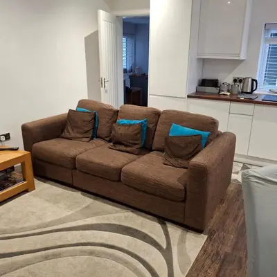 a brown couch with pillows in a living room at Hazel Cottage in Mildenhall