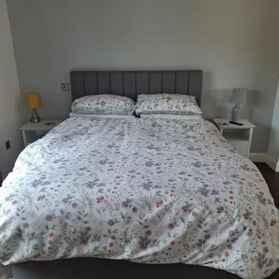 a bedroom with a large bed with a floral comforter at Hazel Cottage in Mildenhall