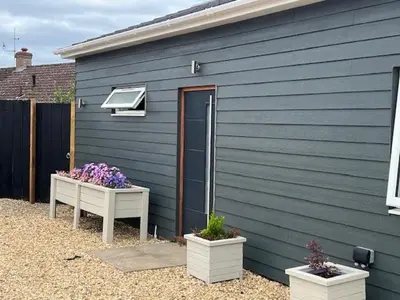 a blue building with two flower pots next to it at Hazel Cottage in Mildenhall
